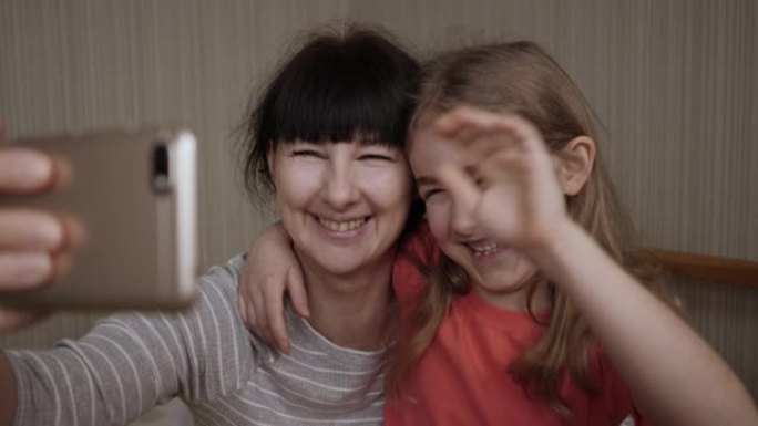 视频通话家庭自拍照。肖像母亲和孩子们在镜头前接吻。快乐的母亲和她的孩子正在床上给父亲或亲戚自拍或视频