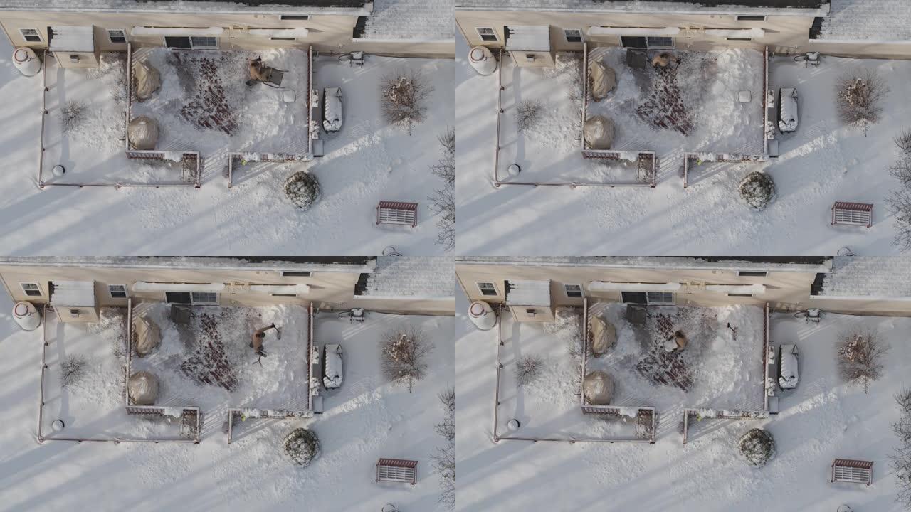 一名成年男子在冬季降雪后用铁锹从雪地上清理门廊。无人机视频正上方的鸟瞰图。