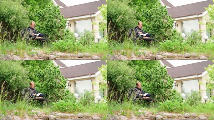金发小女孩盘腿坐在房子后院的长凳上，大声看书，翻页。孩子在乡下度过暑假，绿草在风中挥舞
