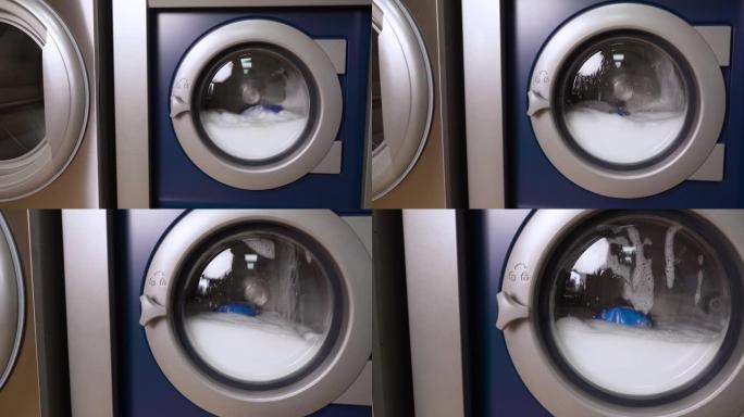 工业洗衣机洗脏彩衣。家用洗衣机洗衣服。旋转滚筒洗衣机的特写视频