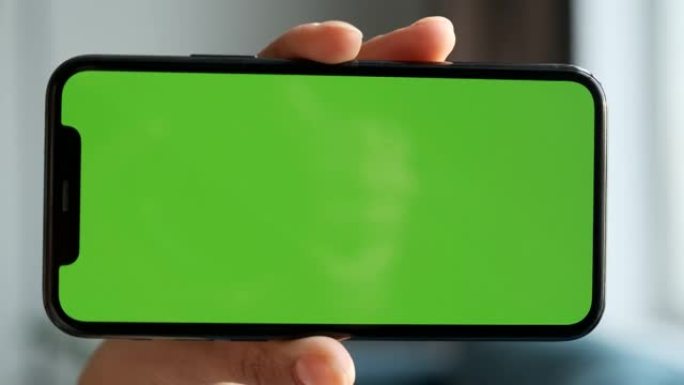 女人的手的特写镜头水平握住带有绿色屏幕的智能手机，用于使用新技术，社交网络，视频，电影和照片的Chr