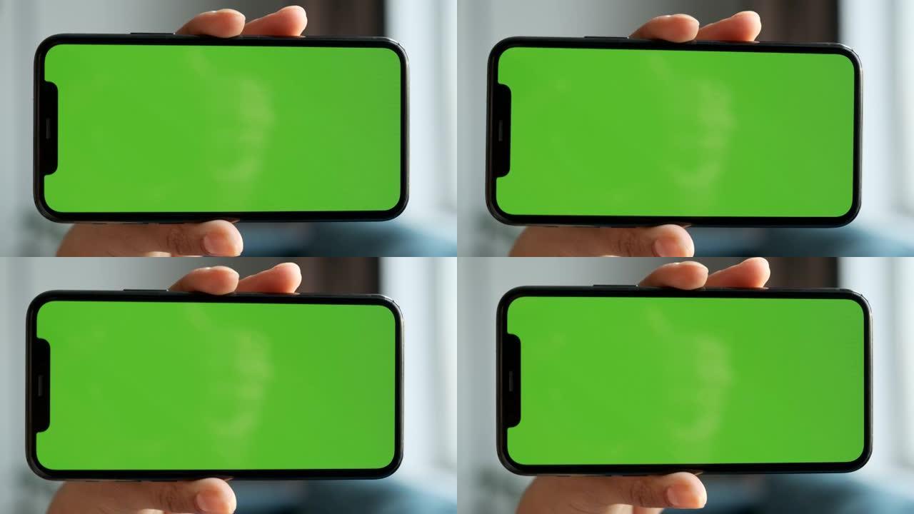 女人的手的特写镜头水平握住带有绿色屏幕的智能手机，用于使用新技术，社交网络，视频，电影和照片的Chr