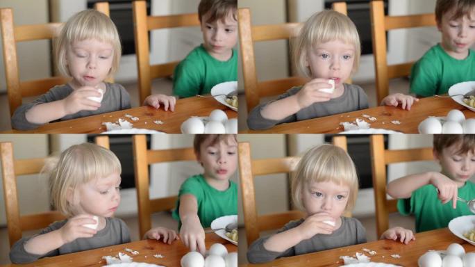 一个可爱的小男孩食欲不振地吃鸡蛋。这个男孩三岁，金发碧眼。