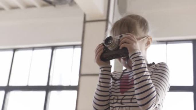 一个年轻女孩学会了用老式相机拍照。行动。小女孩在照片或视频工作室里拿着相机