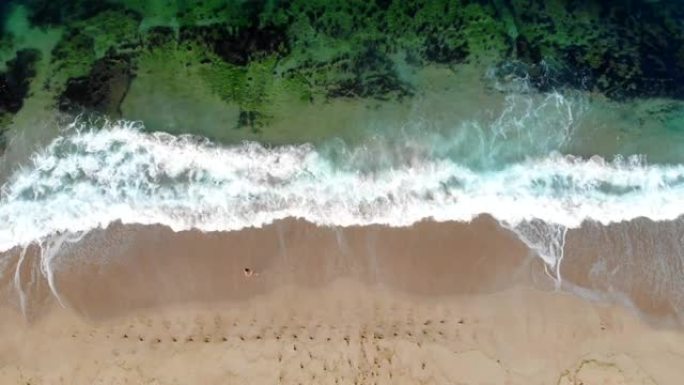 女孩在海岸线上行走的4k视频无人机视图