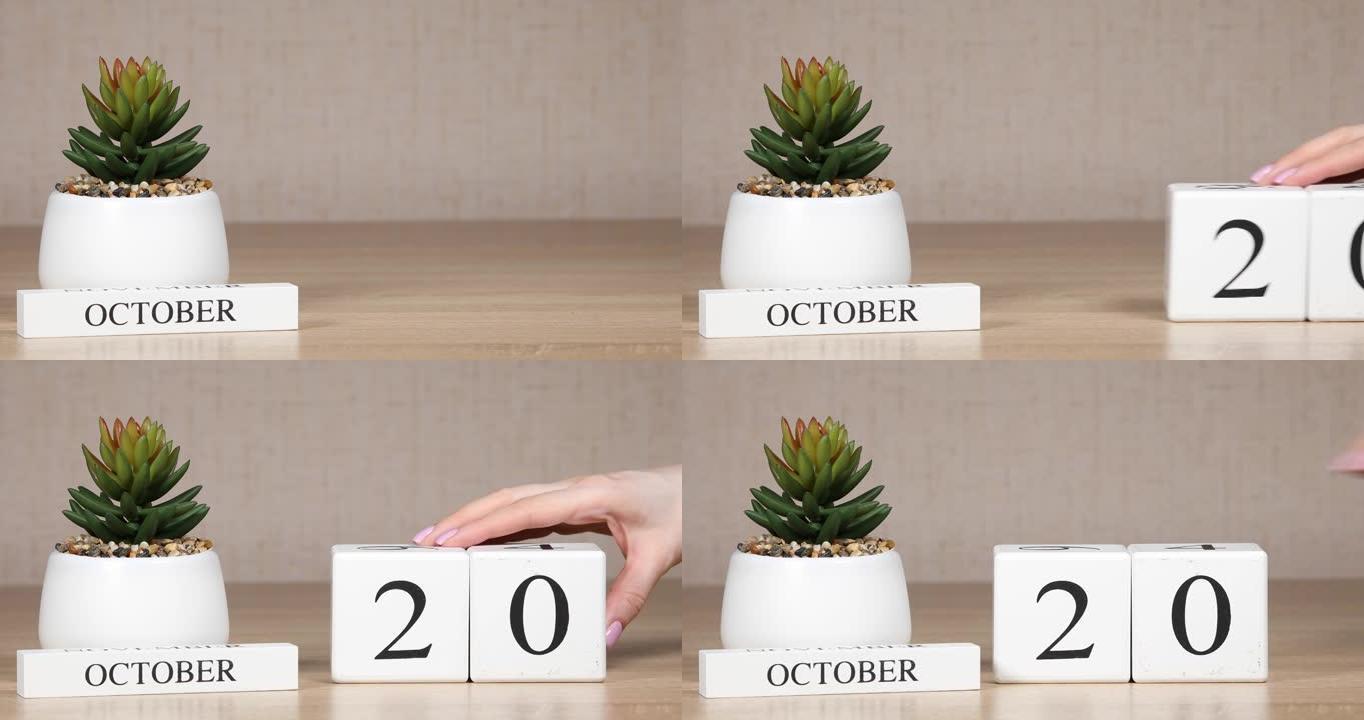 木制日历对10月20日来说是一个重要的事件，女人的手在日历上设置日期。秋季。