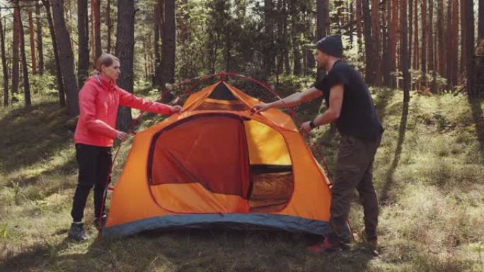 年轻夫妇在森林里一起搭帐篷。户外探险、野营旅行