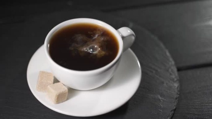 滴奶油滴入咖啡杯。黑木桌上加糖块的芬芳咖啡。
