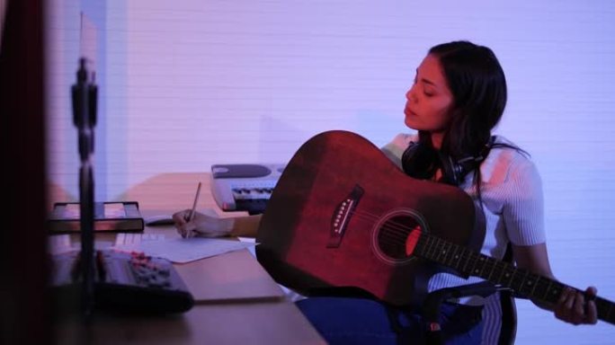 女人在创作新歌时弹吉他并在记事本中写歌词
