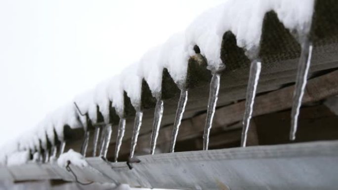 屋顶上的一系列长而薄的融化冰柱