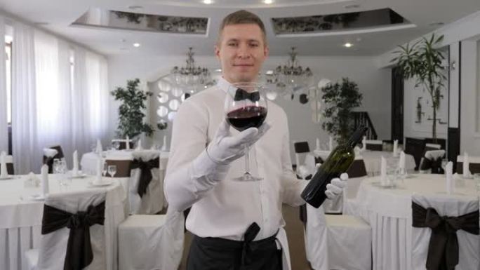 在一家餐馆里，一个男服务员手里拿着一杯红酒的肖像。