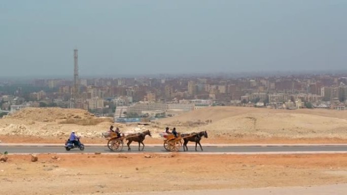 在阿拉伯城市的背景下，马车沿着沙漠中的道路骑行
