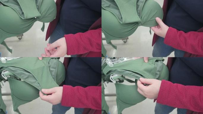 孕妇在店内选择浅绿色泳衣。双手特写镜头