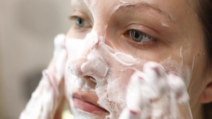 年轻女子正在洗脸，在脸上涂上泡沫清洁剂。日常面部护肤程序。