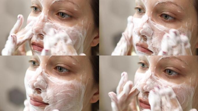 年轻女子正在洗脸，在脸上涂上泡沫清洁剂。日常面部护肤程序。