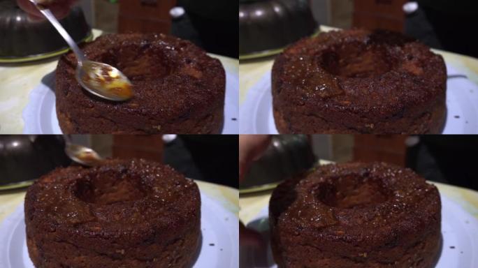 特写镜头将酱汁倒在自制布丁蛋糕上，用勺子放在4k的厨房桌子上