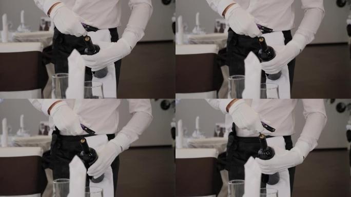 一个戴着白手套的服务员用开瓶器打开一瓶红酒的特写镜头。