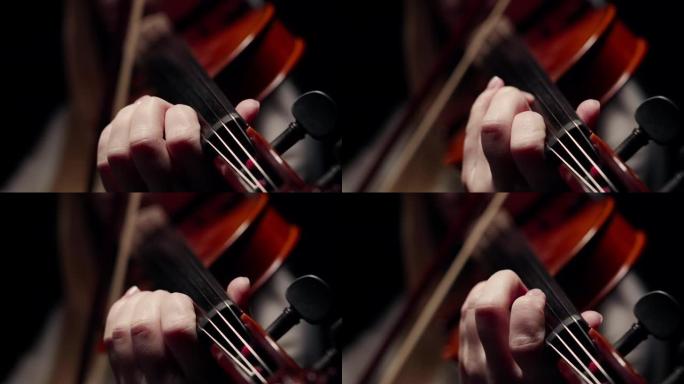 一位女小提琴手手中的小提琴琴颈的特写镜头，在黑暗中用琴弦演奏弓