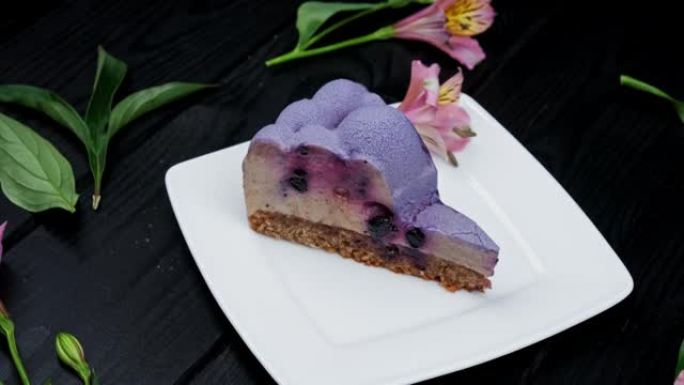在木制背景上的白色盘子上放蓝莓和黑醋栗的芝士蛋糕切片