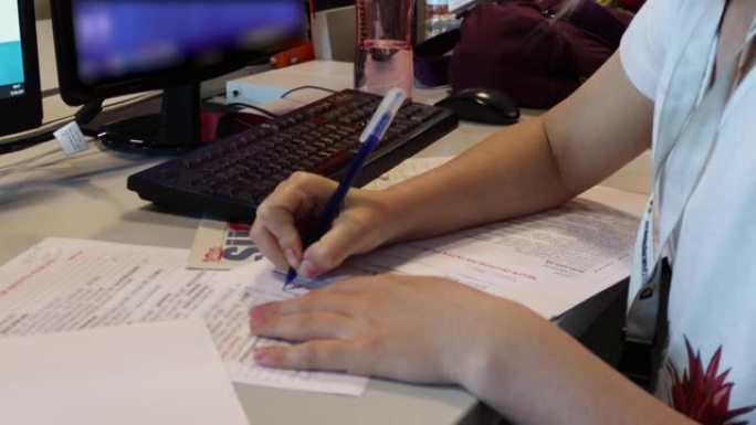特写，女性的手，拿着黑笔，在文件中写东西，在办公室的白色桌面上工作的女商人用图表和图表。