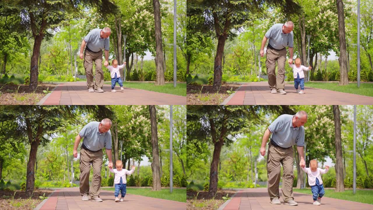 宝贝学会在户外行走。爷爷支持他的孙女教书走路。女婴迈出第一步。