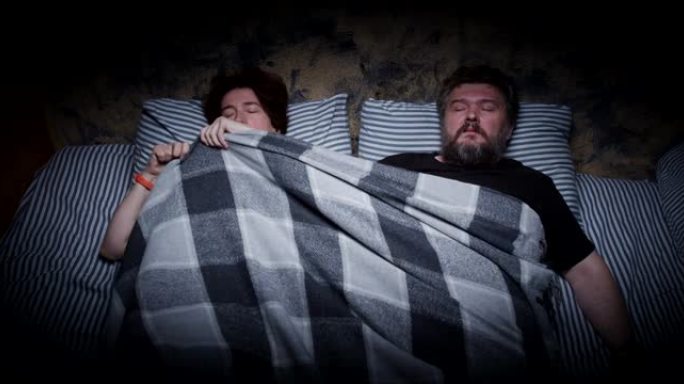 睡觉的妻子在毯子里，丈夫无法入睡
