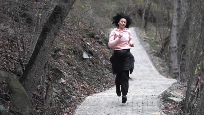 一个健康的女人的慢动作，在秋天森林的乡村小路上慢跑