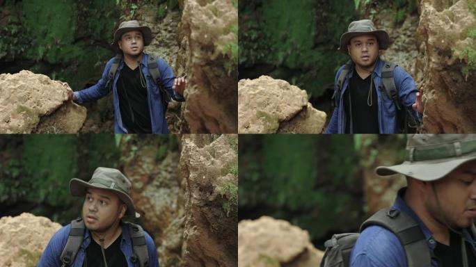 年轻的探险家在许多岩石中旅行。他环顾四周。徒步旅行者在大自然美丽的雨林中旅行。亚洲年轻人在森林中旅行