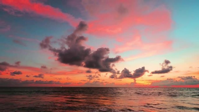 柔和的粉红色日落蓝天，海水上有五颜六色的云