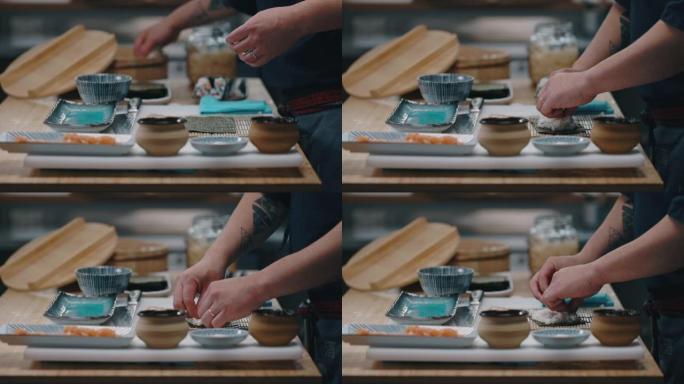 日本厨师在制作寿司maki时将米饭放在紫菜上的侧视图