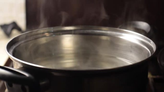 蒸汽从带有水的锅中升起特写，背景模糊