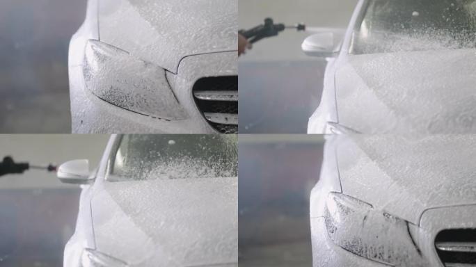 用喷水喷雾和肥皂泡沫清洗白色汽车的人。