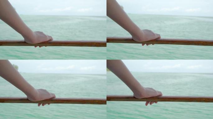 女人的手握着海筏的木栏杆。