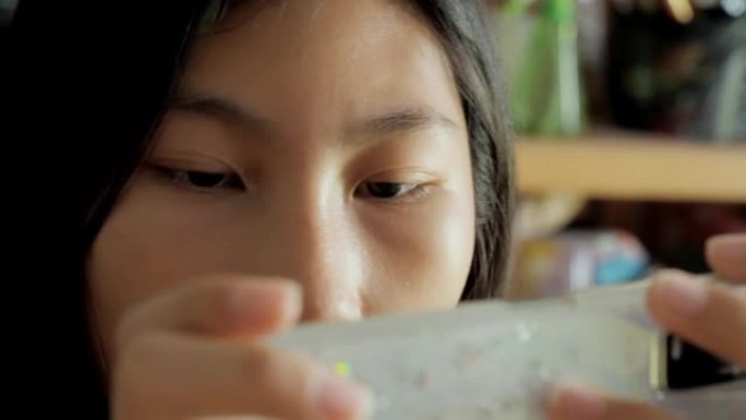 亚洲女孩在家坐在餐桌上玩手机游戏，生活方式理念。
