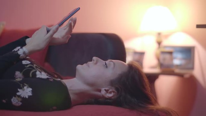 女人躺在床上，脸上投射着智能手机的光