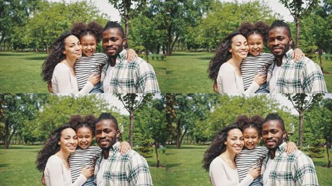 年轻快乐的非洲夫妇父母，一起度过时光，在公园里享受温暖的夏日，和他们可爱的小女儿散步