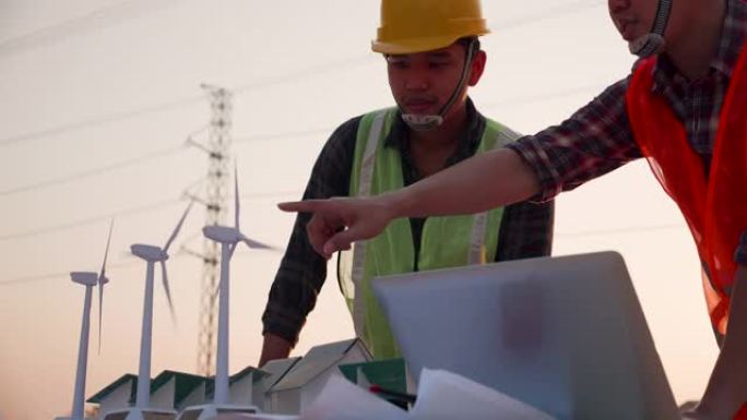 亚洲工程师，领班或领导者讨论建筑工地项目中的家用太阳能电池农场和风力涡轮机模型