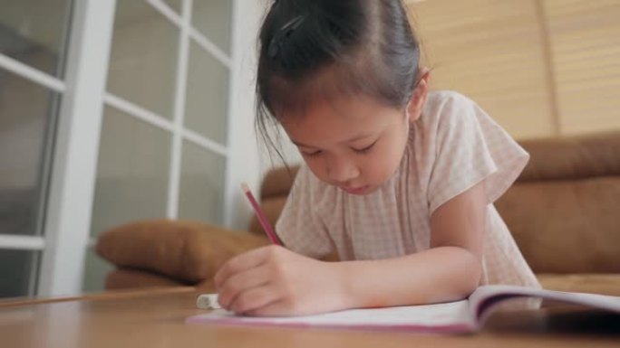 亚洲小女孩在家学习学校练习册上的写作