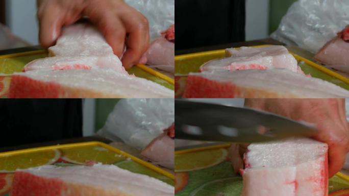 男人正在用刀切一大块猪肉。猪油、猪皮和猪肉切成块。