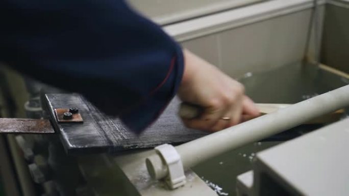 工人用金属刷清洁从电镀浴中取出的零件。拍摄特写