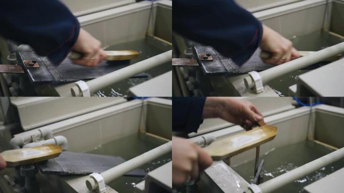 工人用金属刷清洁从电镀浴中取出的零件。拍摄特写