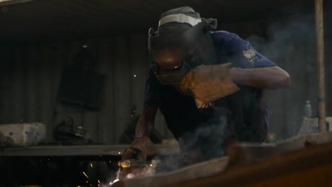 工业工厂机械工人曼钢焊工在工业工厂戴焊接面罩焊钢。