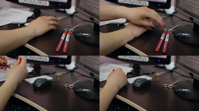 女性手放在电脑键盘上。关闭新型冠状病毒肺炎在桌子上的手和试管的镜头。女人在电脑键盘上点击鼠标。大流行