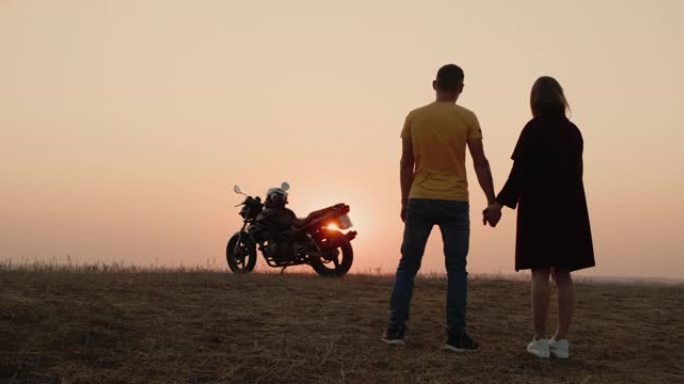 这对浪漫的情侣牵着手，看着前面的摩托车。旅程的开始