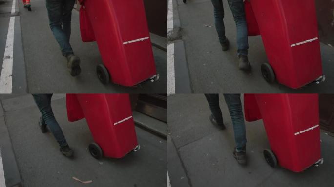一个人腿的运动，一个红色的垃圾桶。城市中的废物收集