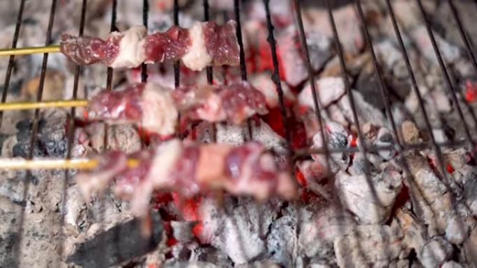 特写街头食品销售商正在烤串上烧烤牛肉。
