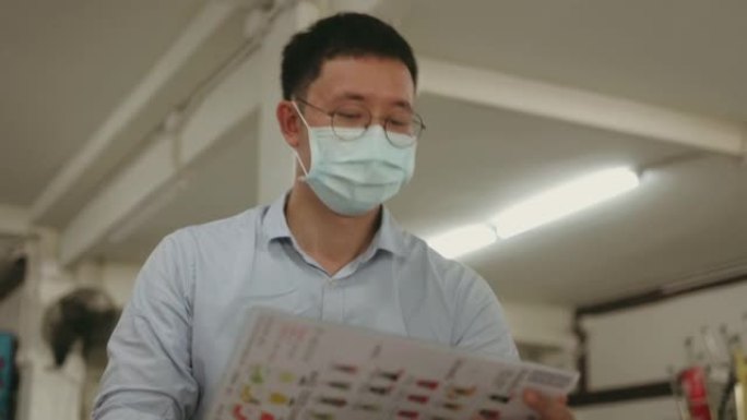 泰国办公室工作人员带防护口罩翻转菜单在病毒流行期间选择当地泰国快餐店的餐饮-库存视频