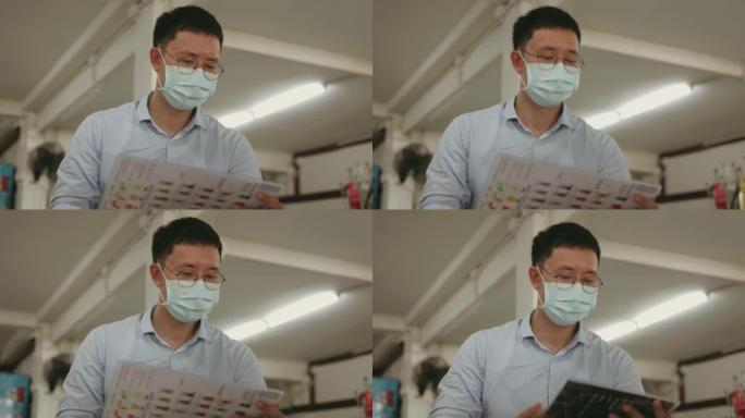 泰国办公室工作人员带防护口罩翻转菜单在病毒流行期间选择当地泰国快餐店的餐饮-库存视频