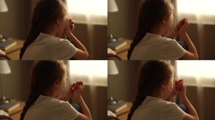 沮丧的小女孩独自坐在窗户背景上的床上哭泣的特写镜头。