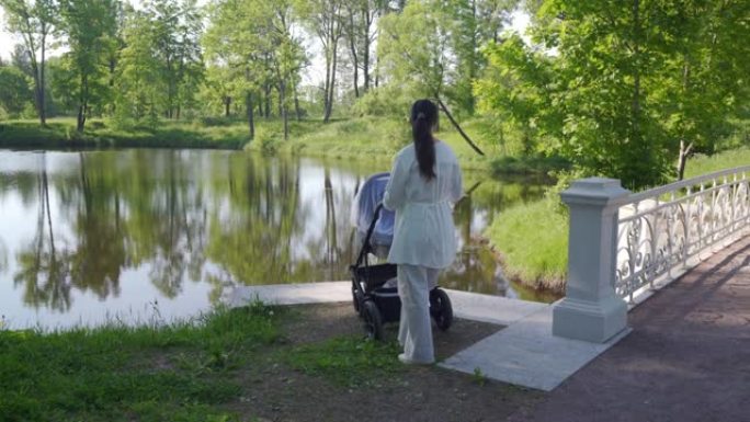母亲带着婴儿车在普希金Tsarskoye Selo镇亚历山大公园的春天公园散步。